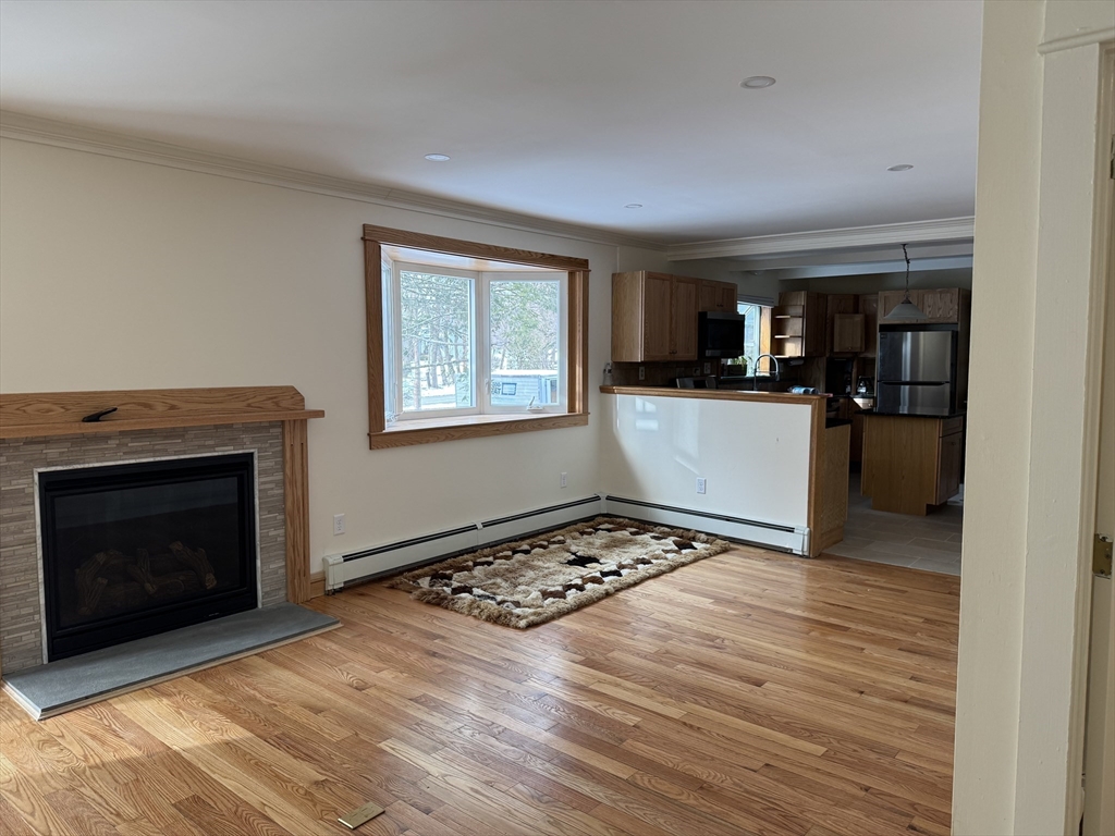 351 Village Street, Unit FIRST Millis, MA 02054 - Photo 2 of 9 a view of a kitchen with wooden floor and a fireplace