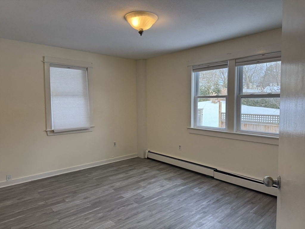 351 Village Street, Unit FIRST Millis, MA 02054 - Photo 6 of 9 an empty room with wooden floor and windows