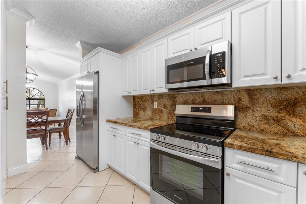 5051 Southwest 142nd Place Miami, FL 33175 - Photo 12 of 30 a kitchen with granite countertop a stove top oven microwave and cabinets