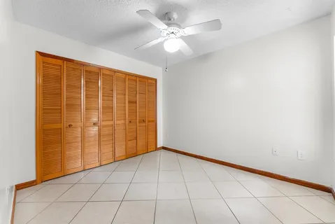 a view of an empty room with window and chandelier fan