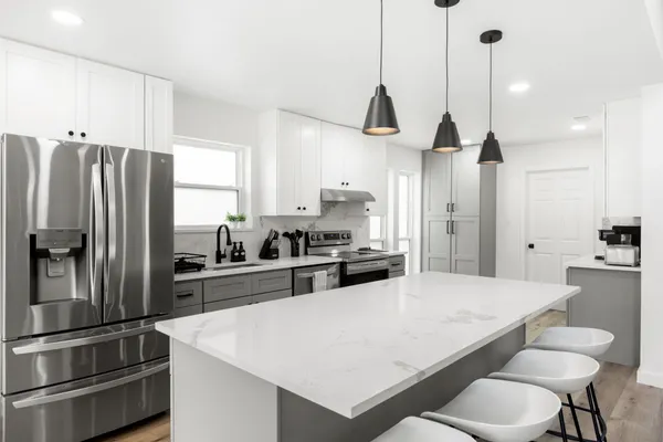a kitchen with a refrigerator a sink and wooden floor