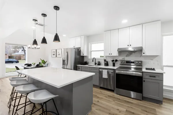 a kitchen with stainless steel appliances kitchen island a table chairs and a sink