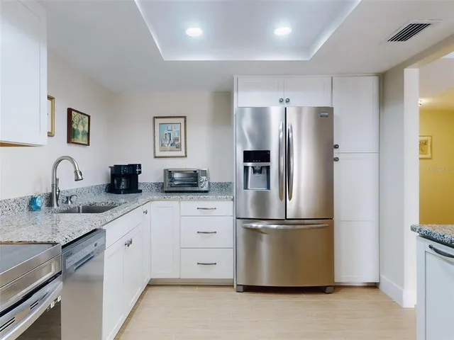 a kitchen with stainless steel appliances granite countertop a refrigerator sink and white cabinets