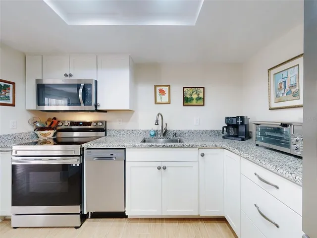 a kitchen with granite countertop a stove top oven sink and cabinets