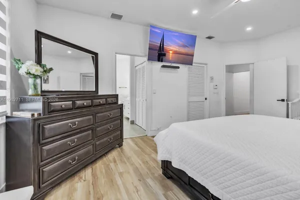 a bedroom with a large bed and wooden floor