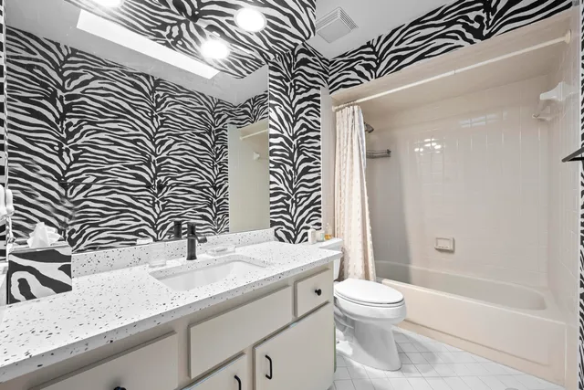 a bathroom with a granite countertop sink a toilet and shower