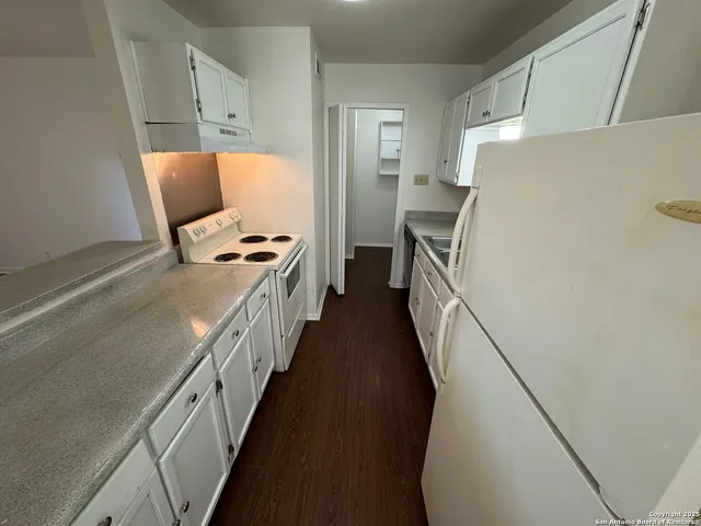 a kitchen with granite countertop a refrigerator a stove and a refrigerator