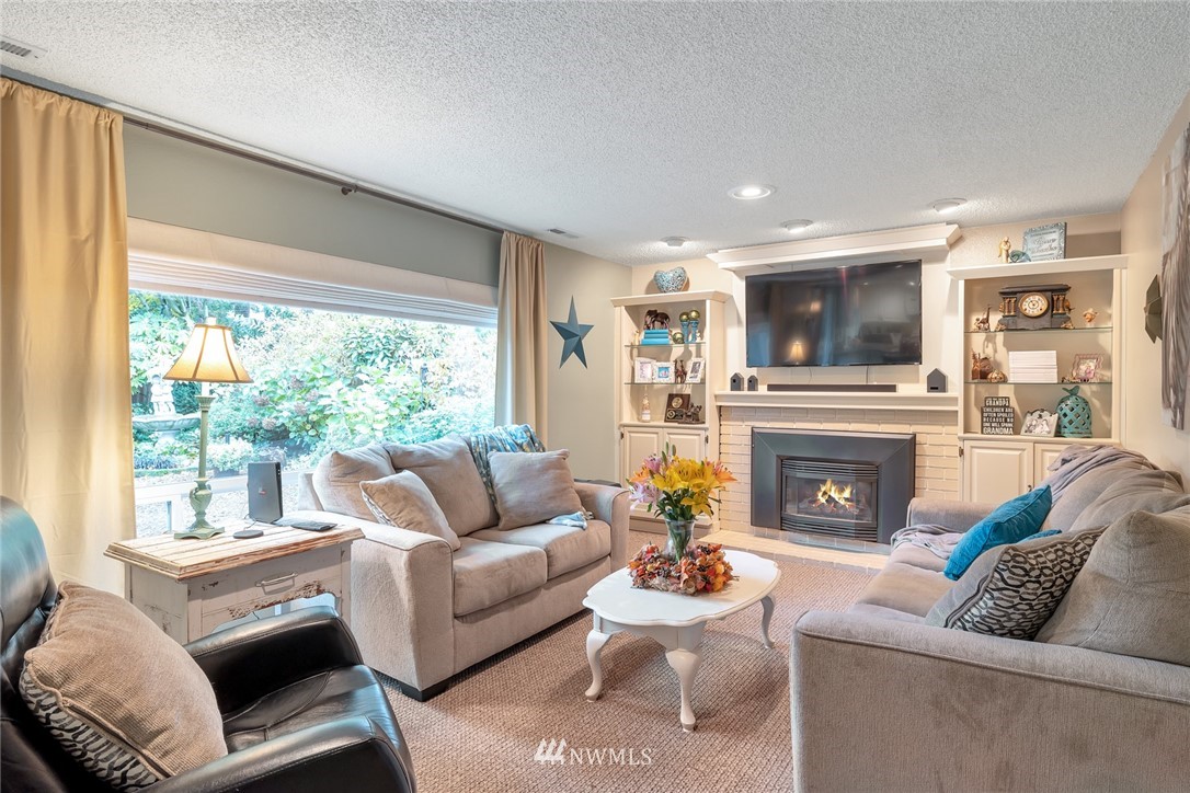 2603 177th Street Southeast Bothell, WA 98012 - Photo 11 of 25 a living room with furniture a fireplace and a large window