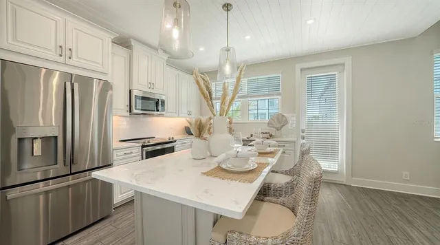 a kitchen with stainless steel appliances granite countertop a kitchen island hardwood floor sink stove dining table and chairs