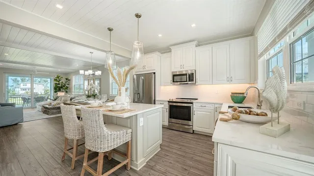 a kitchen with stainless steel appliances kitchen island granite countertop a stove top oven a sink dishwasher a dining table and chairs with wooden floor
