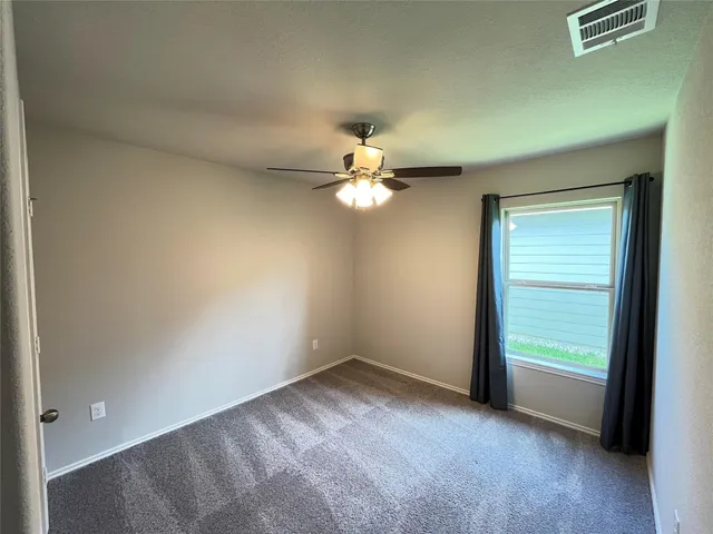 an empty room with a window and a ceiling fan