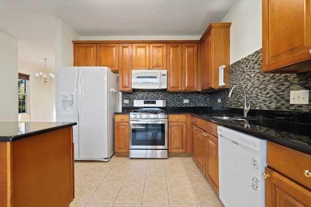 770 Lambert Lane, Unit 966 Bartlett, IL 60103 - Photo 12 of 33 a kitchen with granite countertop a refrigerator stove and sink