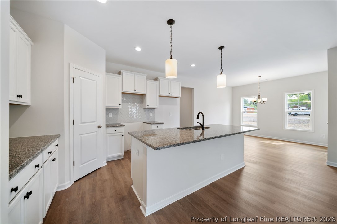 4044 Lofton Street Wade, NC 28395 - Photo 4 of 33 a large kitchen with stainless steel appliances kitchen island granite countertop a refrigerator a sink dishwasher a stove and white cabinets with wooden floor