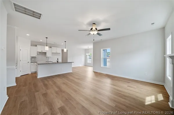 a view of an empty room with kitchen and window
