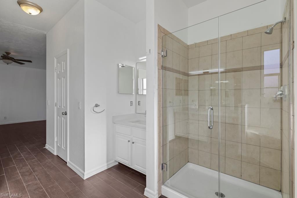 Undisclosed Address Naples, FL 34120 - Photo 11 of 24 Bathroom featuring a shower stall, wood finish floors, and vanity