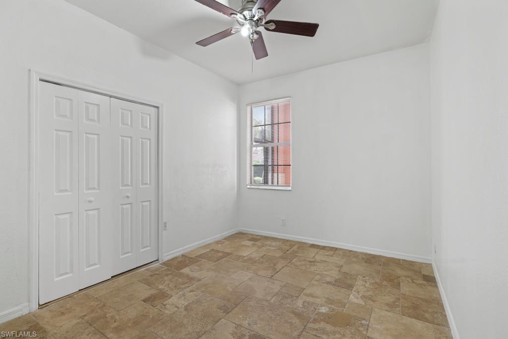 Undisclosed Address Naples, FL 34120 - Photo 13 of 24 Unfurnished bedroom featuring ceiling fan, light stone finish flooring, and a closet