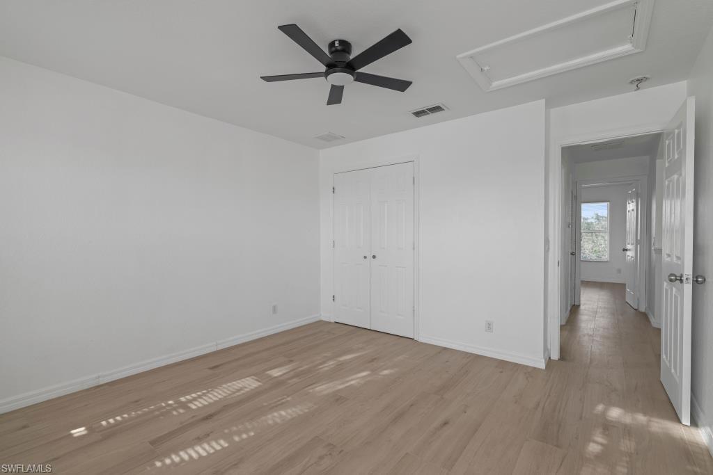 Undisclosed Address Naples, FL 34120 - Photo 16 of 24 Unfurnished bedroom featuring light wood-style flooring, a ceiling fan, and a closet