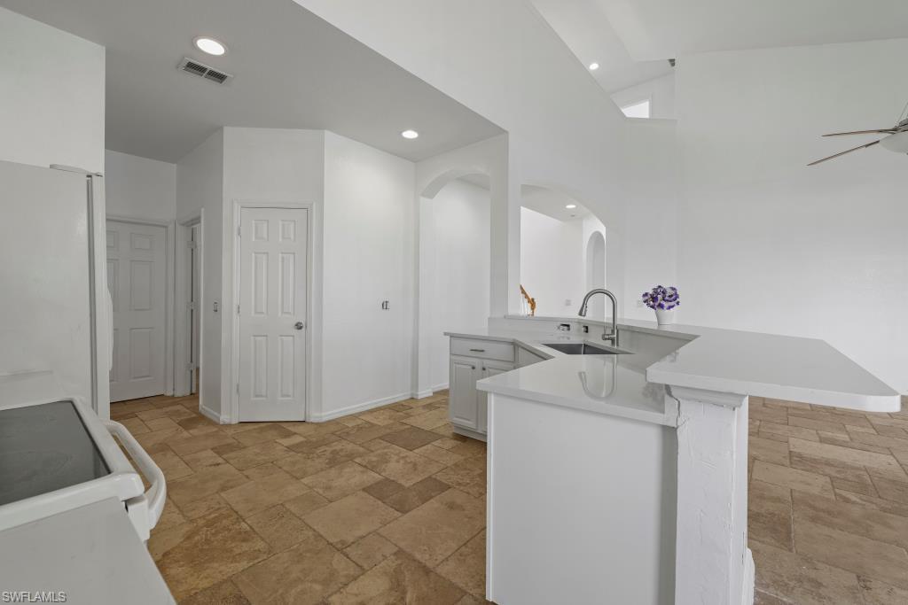 Undisclosed Address Naples, FL 34120 - Photo 6 of 24 Kitchen featuring white cabinetry, range with electric stovetop, freestanding refrigerator, stone tile flooring, and recessed lighting