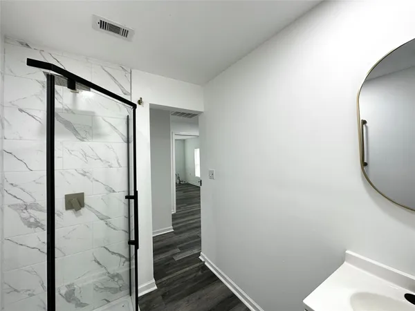 a bathroom with a glass shower door and a mirror