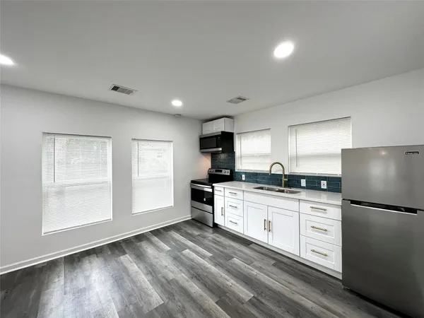 a kitchen with granite countertop a refrigerator stove sink and cabinets