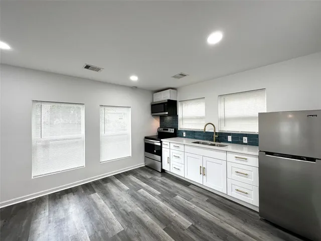 a kitchen with granite countertop a refrigerator stove sink and cabinets