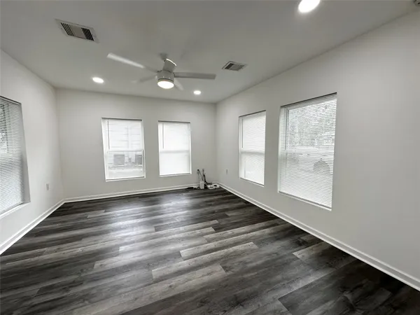 an empty room with wooden floor and windows