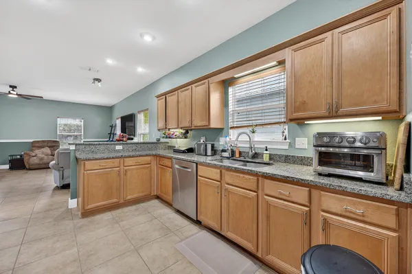 a kitchen with granite countertop wooden cabinets a sink and dishwasher with wooden floor