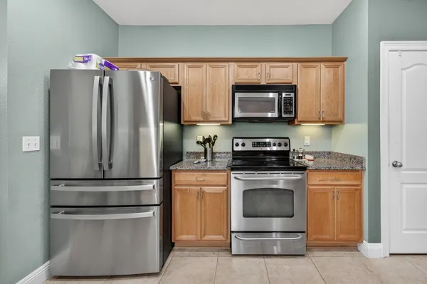 a kitchen with granite countertop stainless steel appliances a stove a microwave and a refrigerator