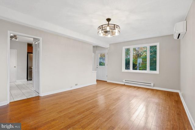 an empty room with wooden floor chandelier and windows