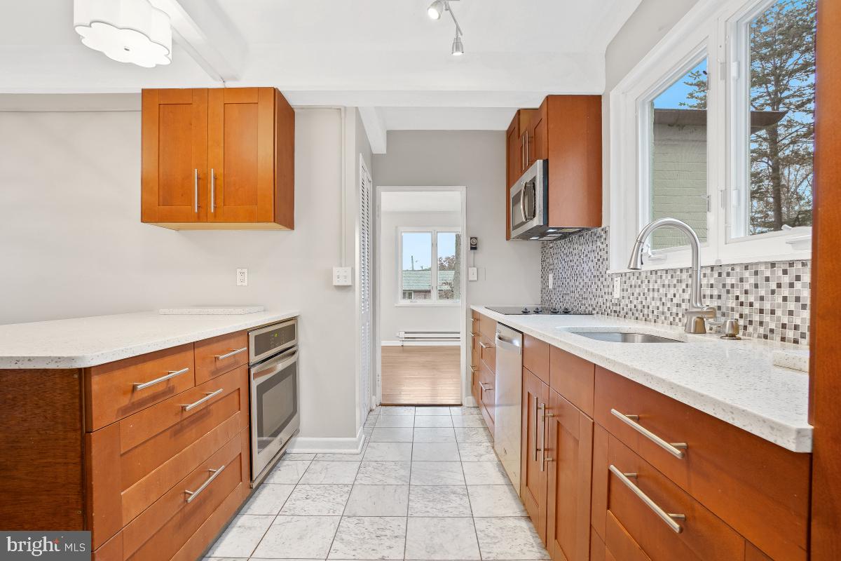 33 Ridge Road Greenbelt, MD 20770 - Photo 7 of 29 a large kitchen with stainless steel appliances granite countertop a sink and dishwasher a stove with wooden cabinets