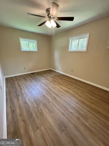 a view of an empty room with a window and wooden floor
