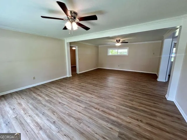 an empty room with wooden floor chandelier fan and windows
