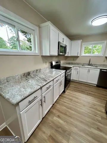a kitchen with stainless steel appliances granite countertop a stove a sink and white cabinets