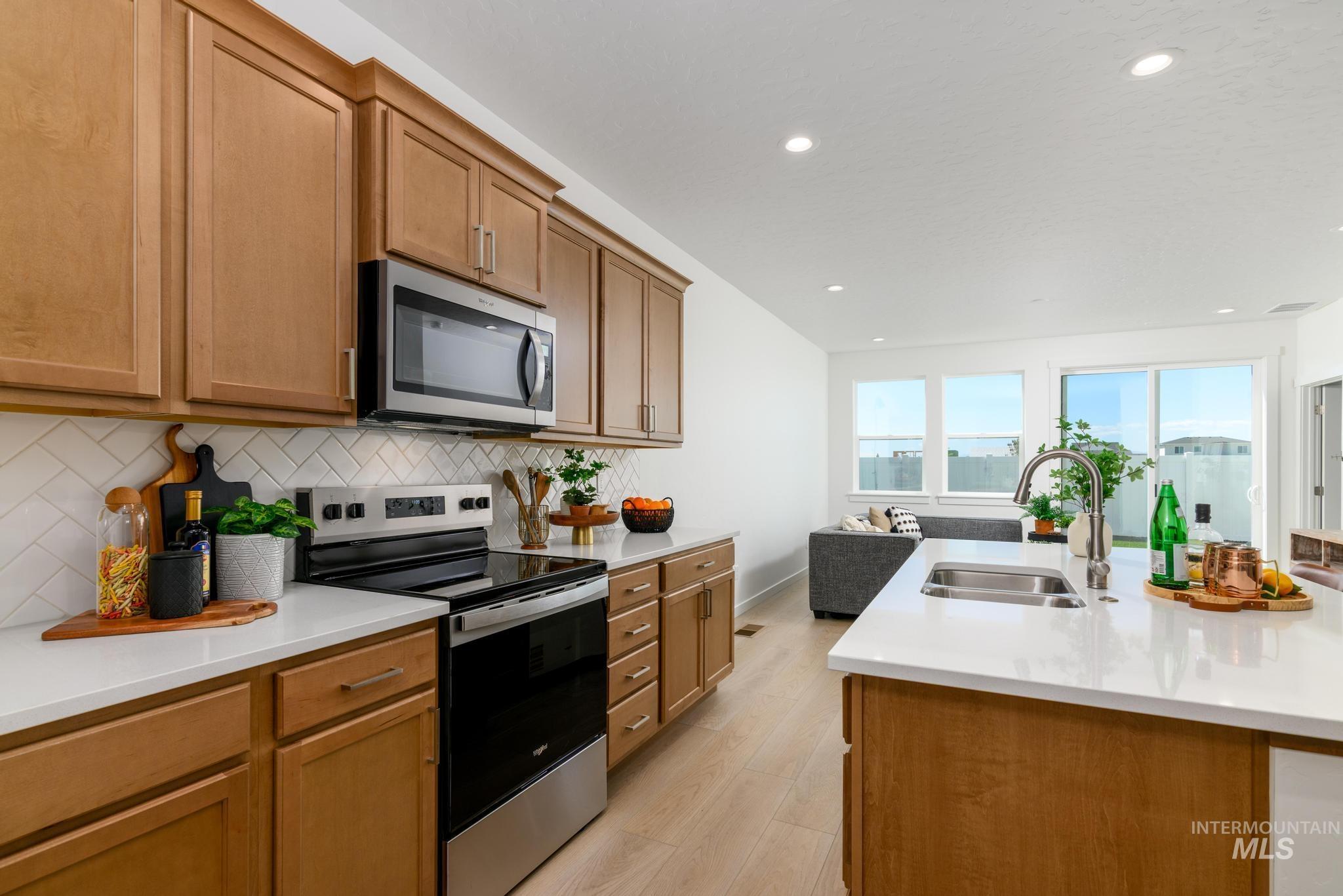 14742 Wing Spread Drive Caldwell, ID 83607 - Photo 4 of 10 Kitchen featuring stainless steel appliances, brown cabinets, light stone counters, light wood-style floors, and recessed lighting