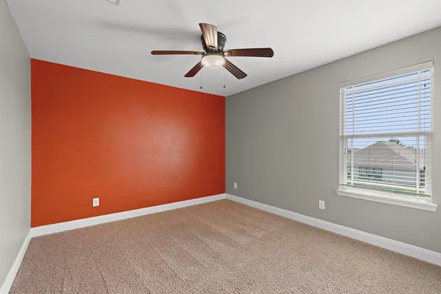 an empty room with ceiling fan and window