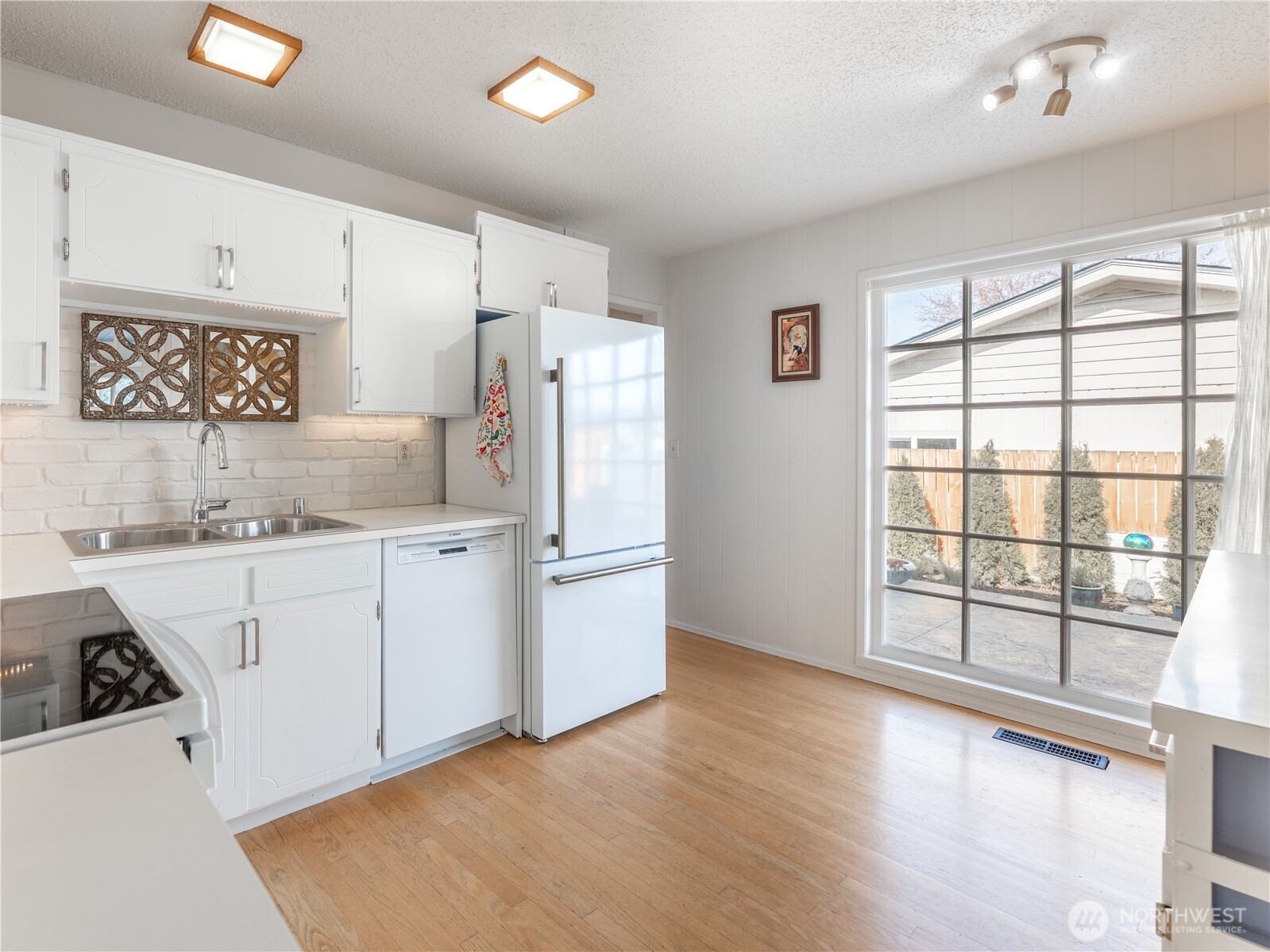 934 Stevens Street Wenatchee, WA 98801 - Photo 11 of 39 a kitchen with granite countertop a refrigerator a sink and white cabinets