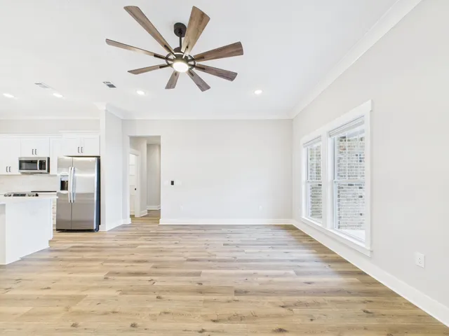 a view of empty room with wooden floor and ceiling fan