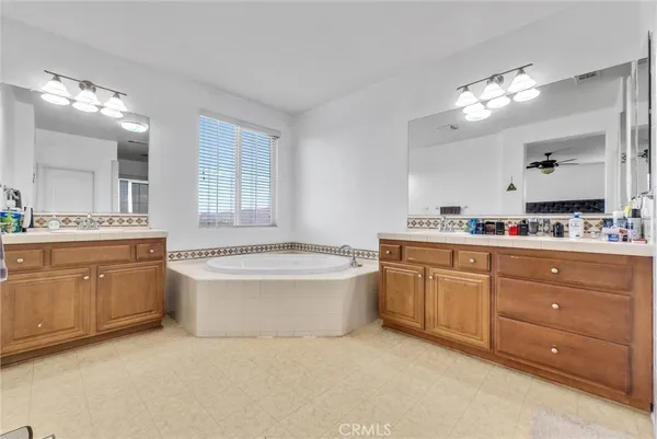 a bathroom with a granite countertop bathtub a sink and a large mirror