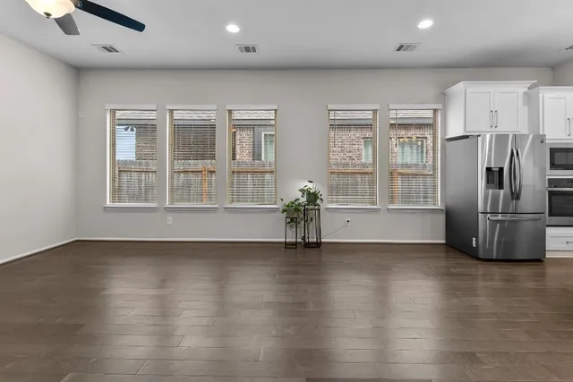 an empty room with wooden floor and windows