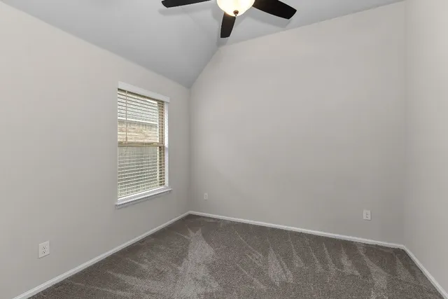 an empty room with chandelier fan and windows