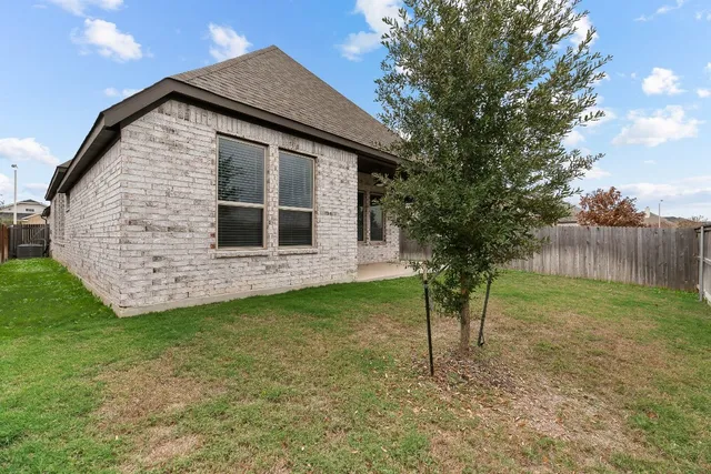 a front view of house with yard and trees in the background