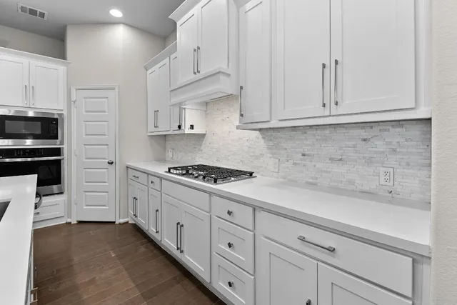 a kitchen with stainless steel appliances granite countertop a sink a stove and a refrigerator