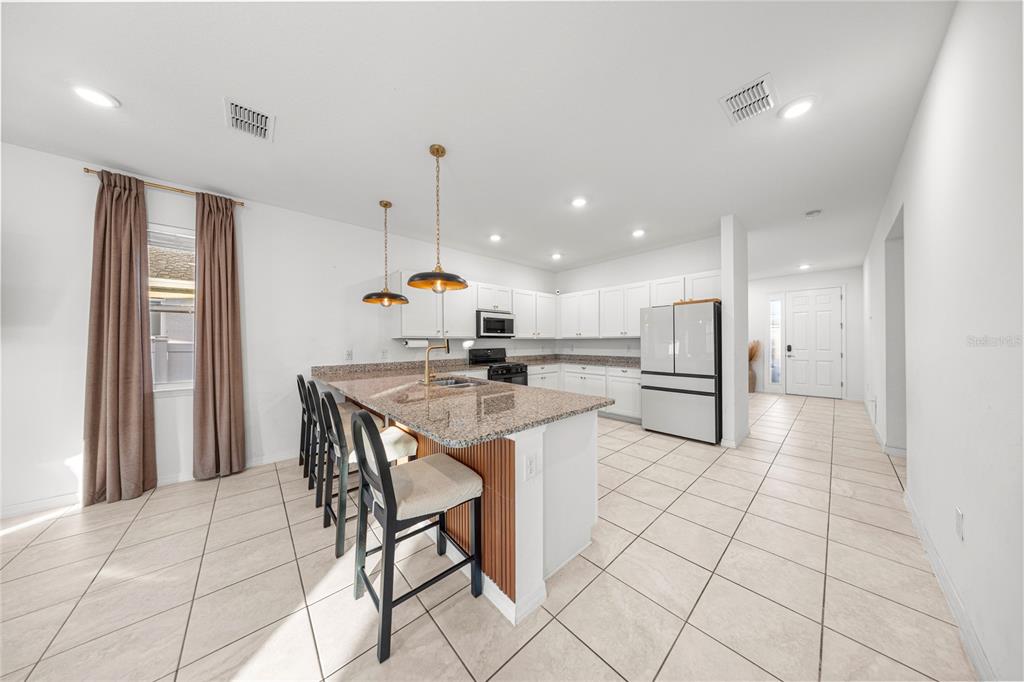 7664 Southwest 63rd Lane Road Ocala, FL 34474 - Photo 9 of 27 a kitchen with stainless steel appliances kitchen island granite countertop a stove a sink and a refrigerator