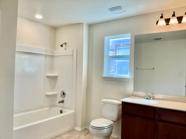 a bathroom with a bathtub shower sink mirror vanity and toilet