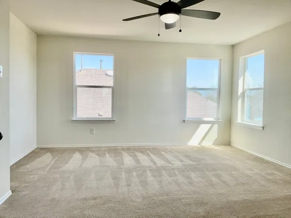 an empty room with windows and fan