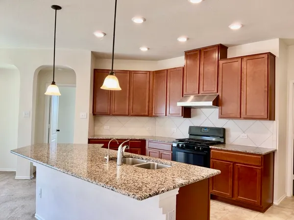 a kitchen with kitchen island granite countertop a sink a counter space appliances and cabinets