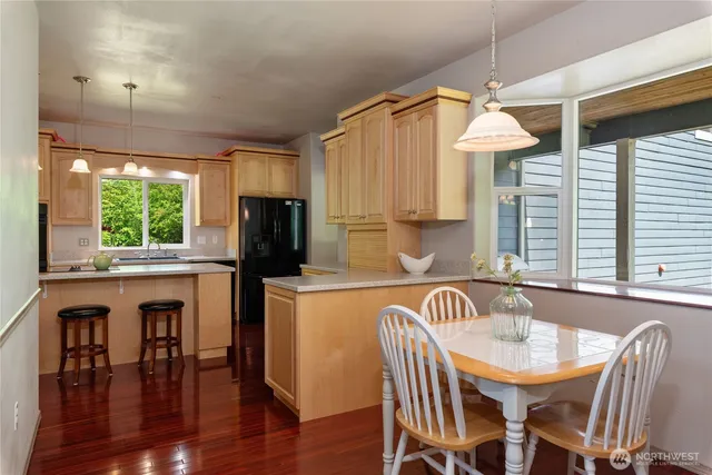 a kitchen with stainless steel appliances granite countertop a dining table chairs and a refrigerator