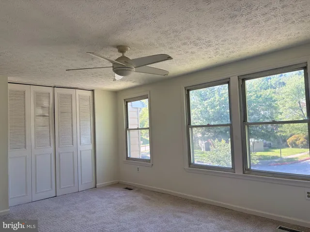 an empty room with windows and ceiling fan