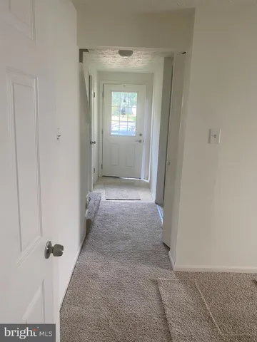 a view of a hallway with wooden floor and a livingroom