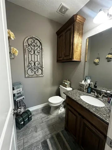 a bathroom with a granite countertop toilet sink and mirror